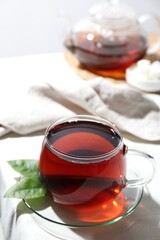 Refreshing black tea in cup on light table, closeup