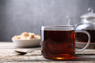 Aromatic black tea in cup on wooden table, closeup