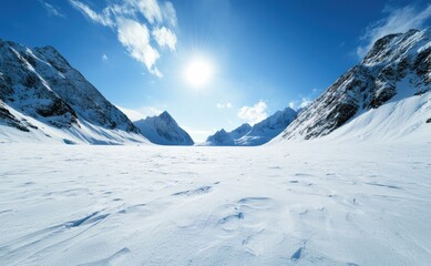 Obraz premium A stunning view of snow-covered mountains under a bright blue sky, with a radiant sun shining over a vast frozen landscape.