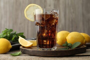 Fresh iced cola with mint and lemons on wooden table, closeup