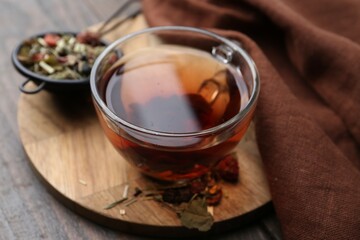 Delicious herbal tea and dry leaves on wooden table, closeup