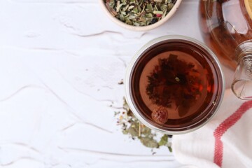 Delicious herbal tea and dry leaves on white table, flat lay. Space for text