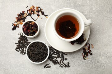 Aromatic tea and dried leaves on grey table, flat lay