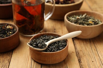 Aromatic tea and dried leaves on wooden table, closeup