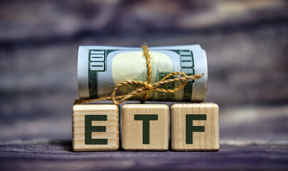 ETF text on wooden cubes with dollars 100 bills