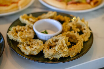 Fried onion rings on a serving plate on the table with other food