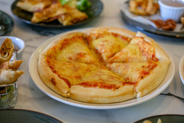 Cheese pizza on the table with other dishes