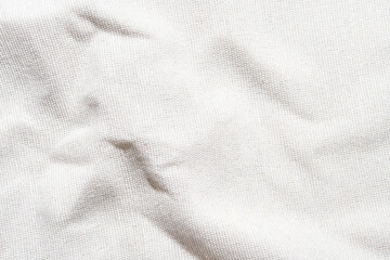 Close-up texture of white wrinkled canvas fabric with subtle shadows.