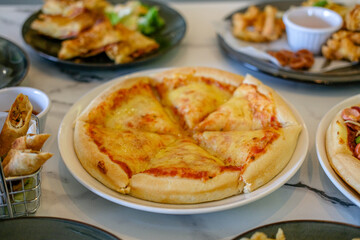 Cheese pizza on the table with other dishes