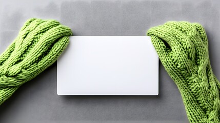 Fototapeta premium Green Knitted Gloves Holding Blank White Card Mockup