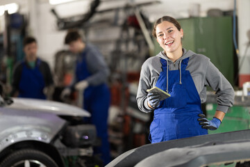 Girl employee performs repairs to external parts of car body and internal components of vehicle....
