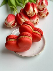Red macarons on the white plate and fresh red tulips