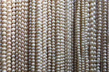 Close up of thick strings of white pearls hanging on shop display