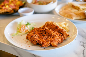 Chicken katsu on white plate with vegetables and french fries