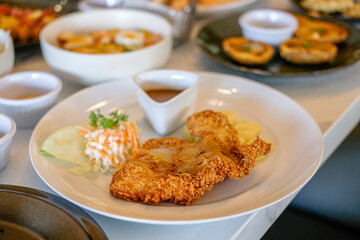 Chicken katsu on white plate with vegetables and french fries