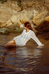 beautiful young girl sitting on sea beach, in sea