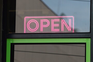 A neon sign that says "open" is lit up in a window