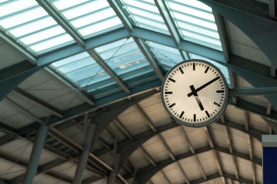 A clock hanging from the ceiling in a train station