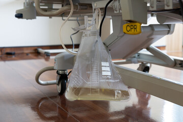 urine bag under patient bed in hospital room