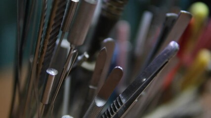 A collection of various metal tools with different handles, arranged closely together, showing a detailed close-up with a shallow depth of field, emphasizing craftsmanship and precision work