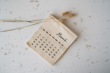 Beige linen fabric calendar with March month 2025 on a white background with copy space. Flat lay, template. Minimal top view aesthetic composition. Stylish, trend concept. Parisian vibes.