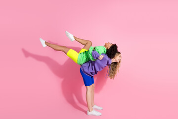 Vibrant image featuring two joyful friends in colorful casual clothing posing playfully against a pink background