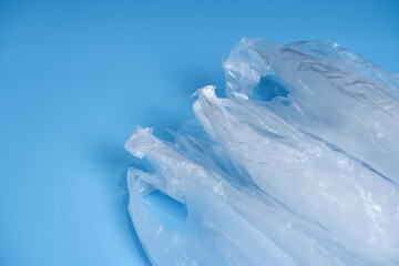 Used plastic bag with crumpled texture placed on blue background. Close-up plastic bag handles with copy space. Concept of wrinkle, wrap, household use, crumpled texture, clean, and abstract.