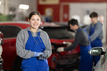 Fototapeta premium Portrait of a positive girl auto mechanic in the interior of a car service