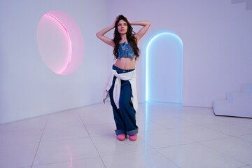 Young woman posing in modern indoor space with colorful lighting effects