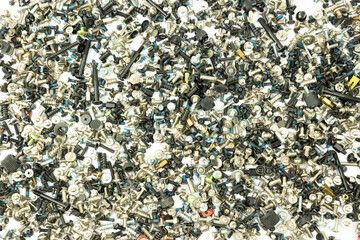 A chaotic assortment of various screws, bolts, and fasteners in mixed metallic and black tones, scattered randomly on a white background