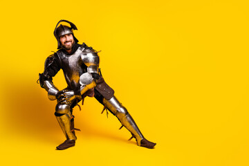Young man in knight armor kneeling on a vibrant yellow background portraying historical character