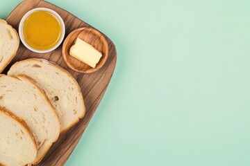 Freshly sliced bread arranged on wooden board with butter and ho