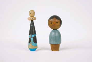 Traditional Japanese wood dolls on a white table.