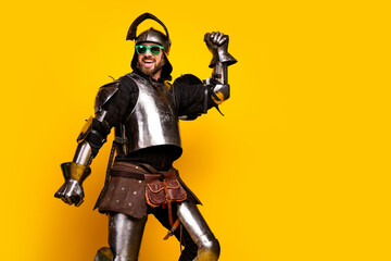 Armored man mixing medieval and modern styles with bright sunglasses on a vivid yellow background.