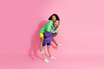 Cheerful young women having fun together in colorful casual outfits and pink backdrop