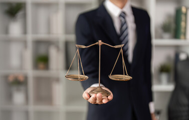 Young Asian lawyer presenting legal scales in office, symbolizing justice and balance in law practice.