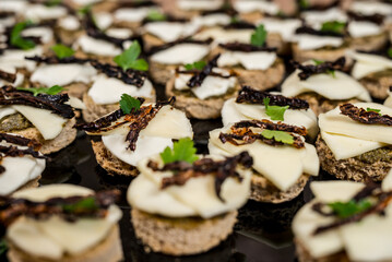 Close up of a large platter of bite sized appetizers for a party featuring cheese and vegetable toppings