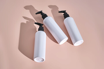 Three white bottles of bath products on a powdery pink background.