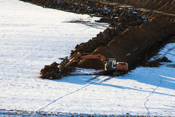 close-up Road construction. Excavator digs a trench for laying a sewer pipe on a cloudy winter day. Selective focus, shallow depth of field