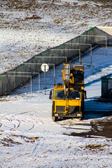 yellow crane in the winter on the construction site, clean the snow in the fog and the sun