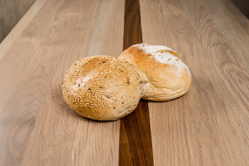 Two freshly baked rolls one with sesame seeds sit invitingly on a wooden surface Ready to be enjoyed