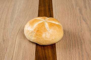 Crisp bread roll on a dark and light wood table Warm pastry a starburst of scored markings