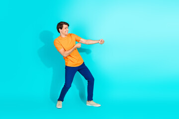 Cheerful young man gestures energetically in colorful casual outfit against vibrant teal backdrop, expressing fun and energetic style
