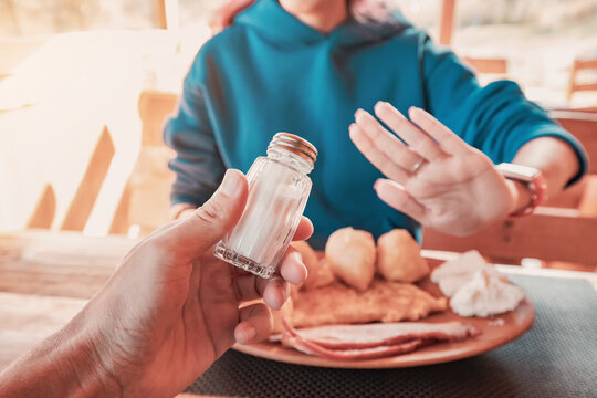 Woman refusing salt shaker offered by waiter, following a healthy diet and lifestyle, avoiding sodium intake