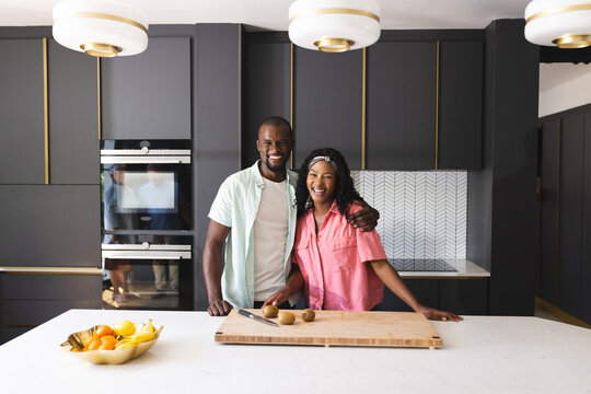 Smiling diverse couple preparing meal in modern kitchen, enjoying quality time, at home