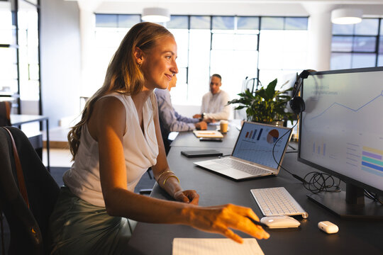 Analyzing data on computer, businesswoman in modern office, smiling confidently