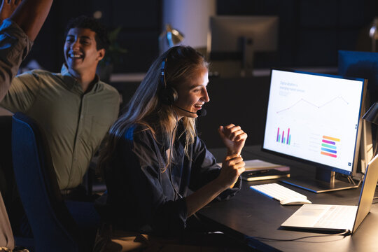 Businesswoman wearing headset analyzing data on computer at night office