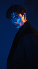 Fototapeta premium Dramatic High-Contrast Portrait of a Male Model in Moody Lighting, Featuring Fashion Aesthetics with Strong Shadows and Bold Color Accents