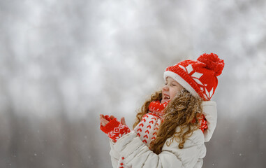 Cute little girl stretches her hand to catch falling snowflakes. First snow.