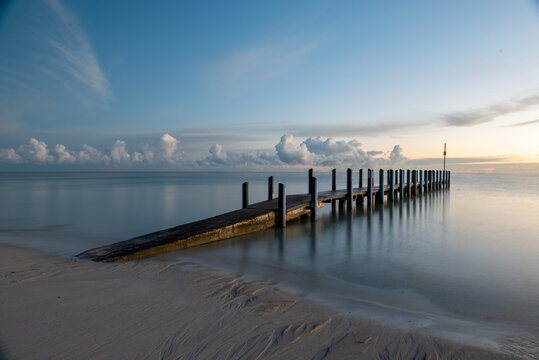 jetty in ocean long exposure with clouds at sunrise